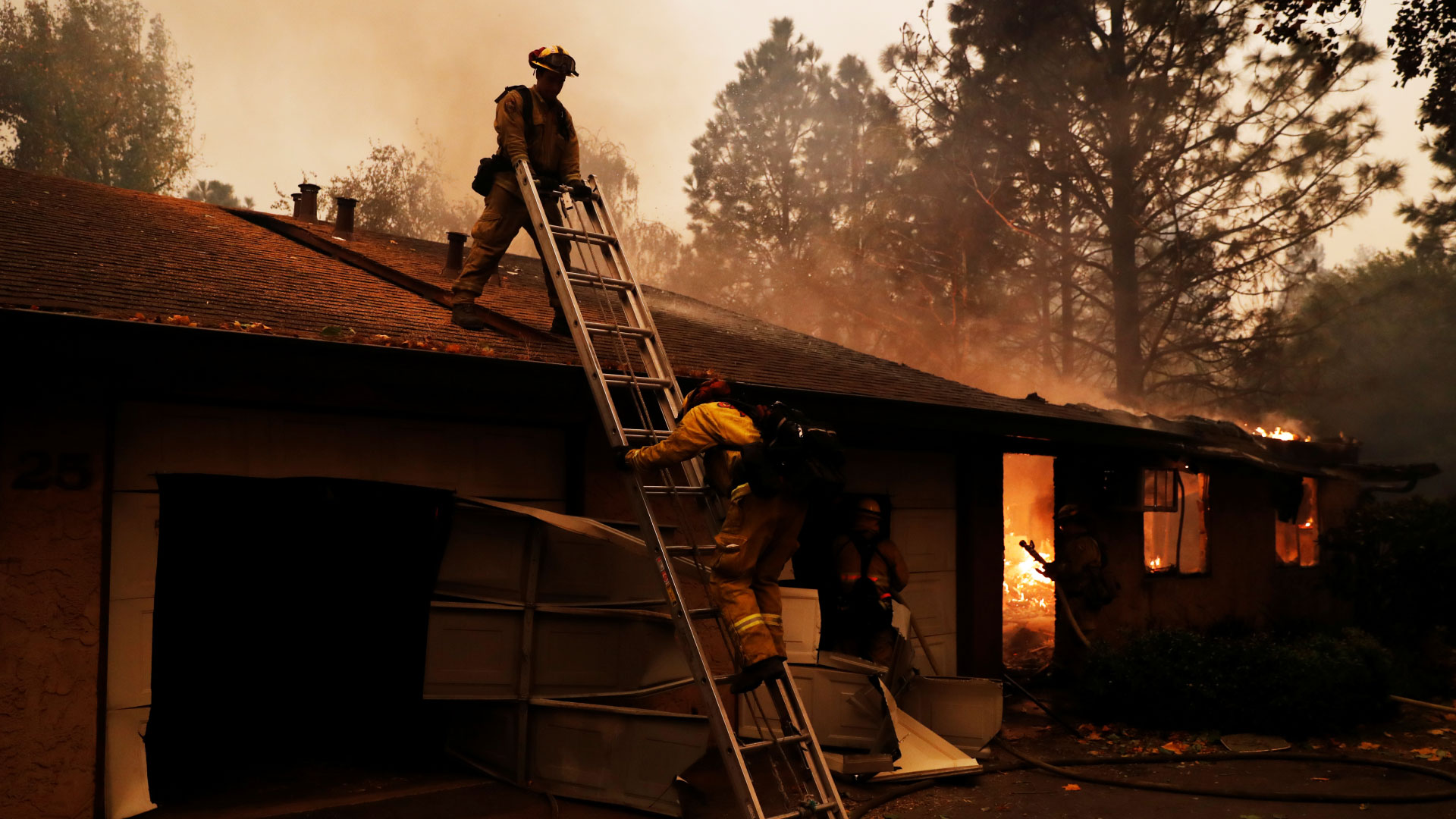  Cal Fire firefighter climbs a ladder by a burning structure while battling the Camp Fire in Paradise, California, U.S., November 9, 2018