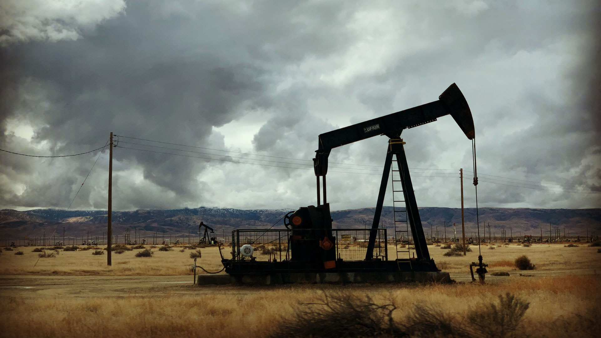 Oil well in field with storm clouds in the background