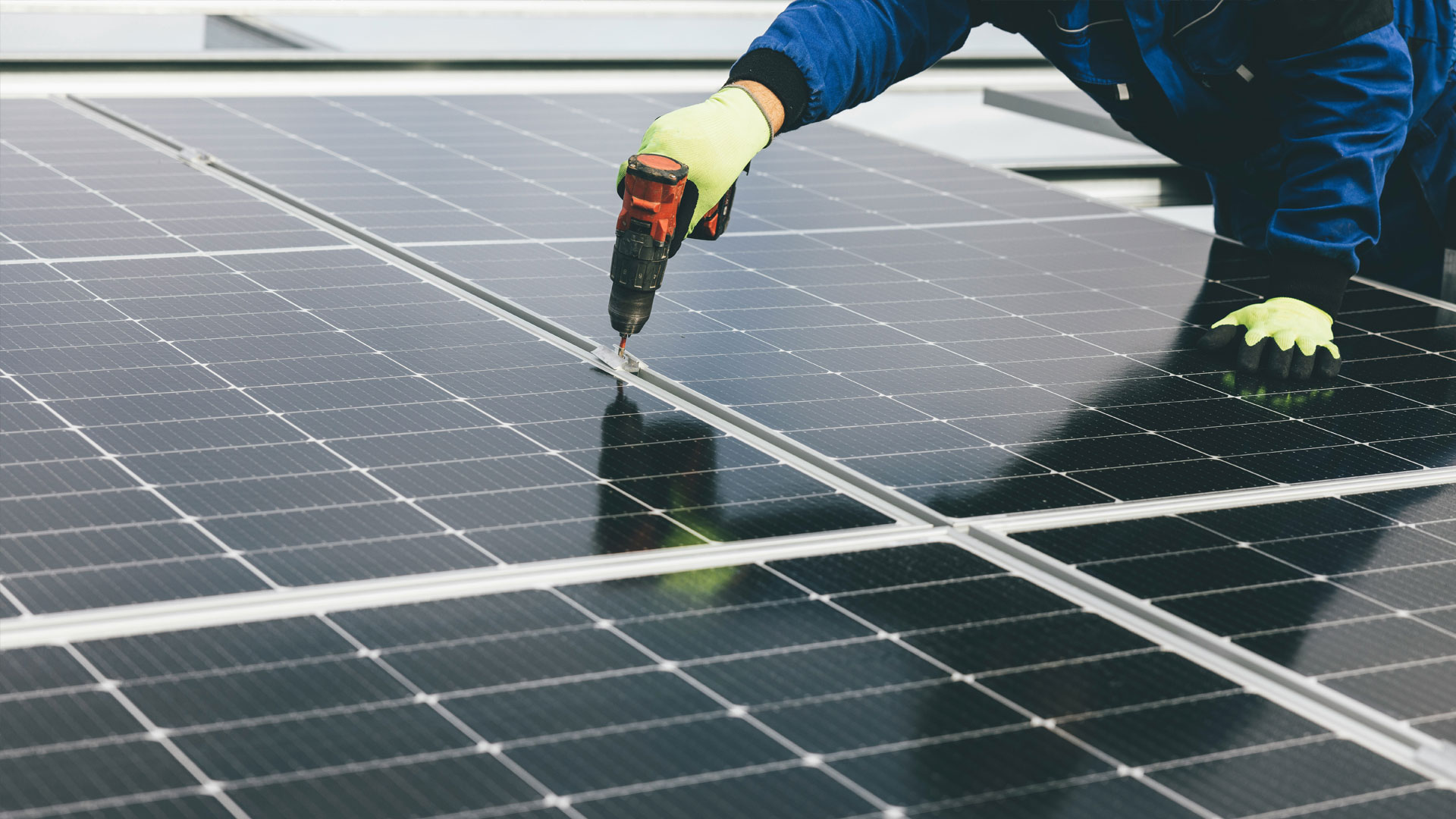Worker installing solar panels on rooftop