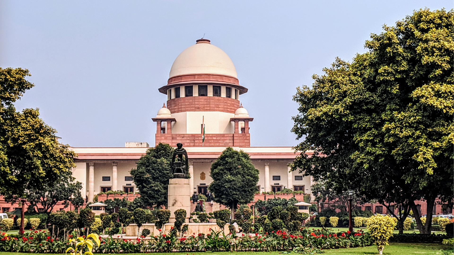 The dome of the Supreme Court of India with a statue and garden in the foreground.