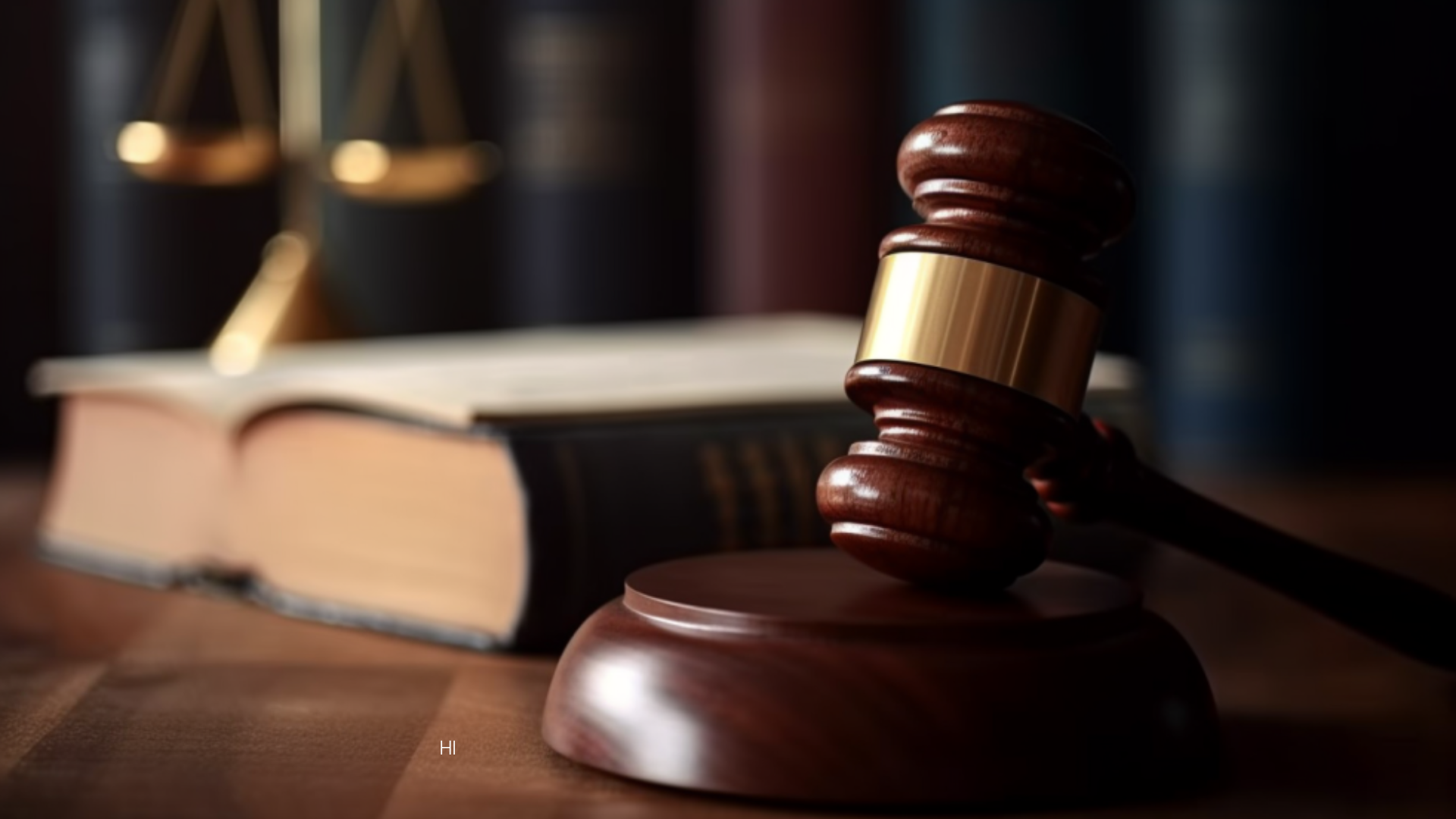 A judge's gavel sits in front of a large book with the scales of justice in the background.